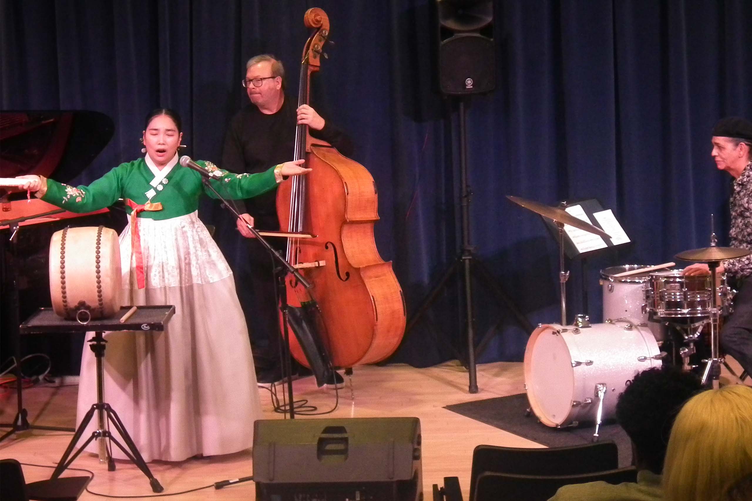 heewon park pansori kpai 2 A singer attired in traditional Korean costume performs with a bassist and a drummer, with audience seated in the foreground.