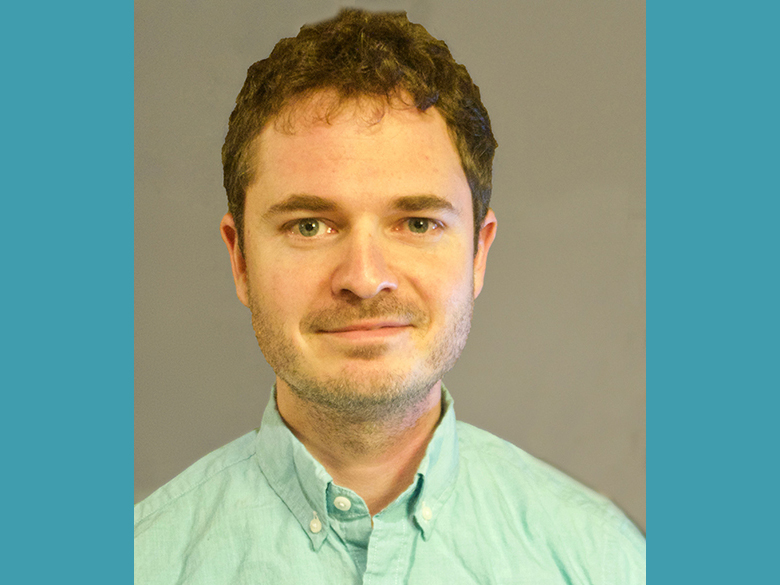 Headshot of Jeremy Edwards with a teal blue background.