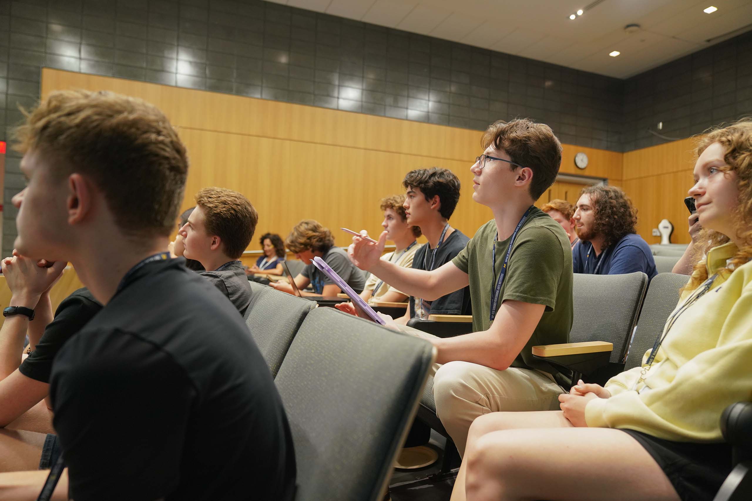 A group of students are shown in a lecture looking up and paying attention