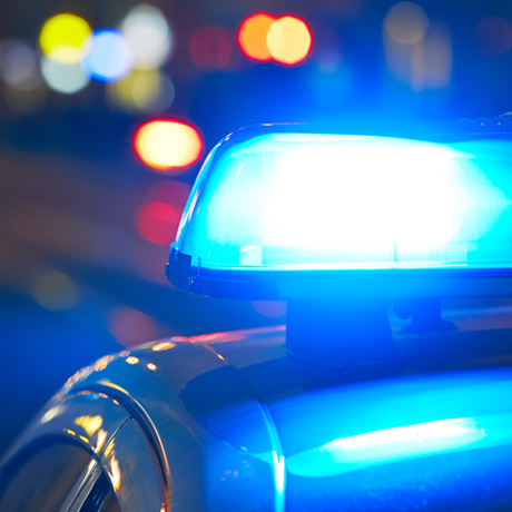 Detail of a blue emergency light atop a police vehicle at night.