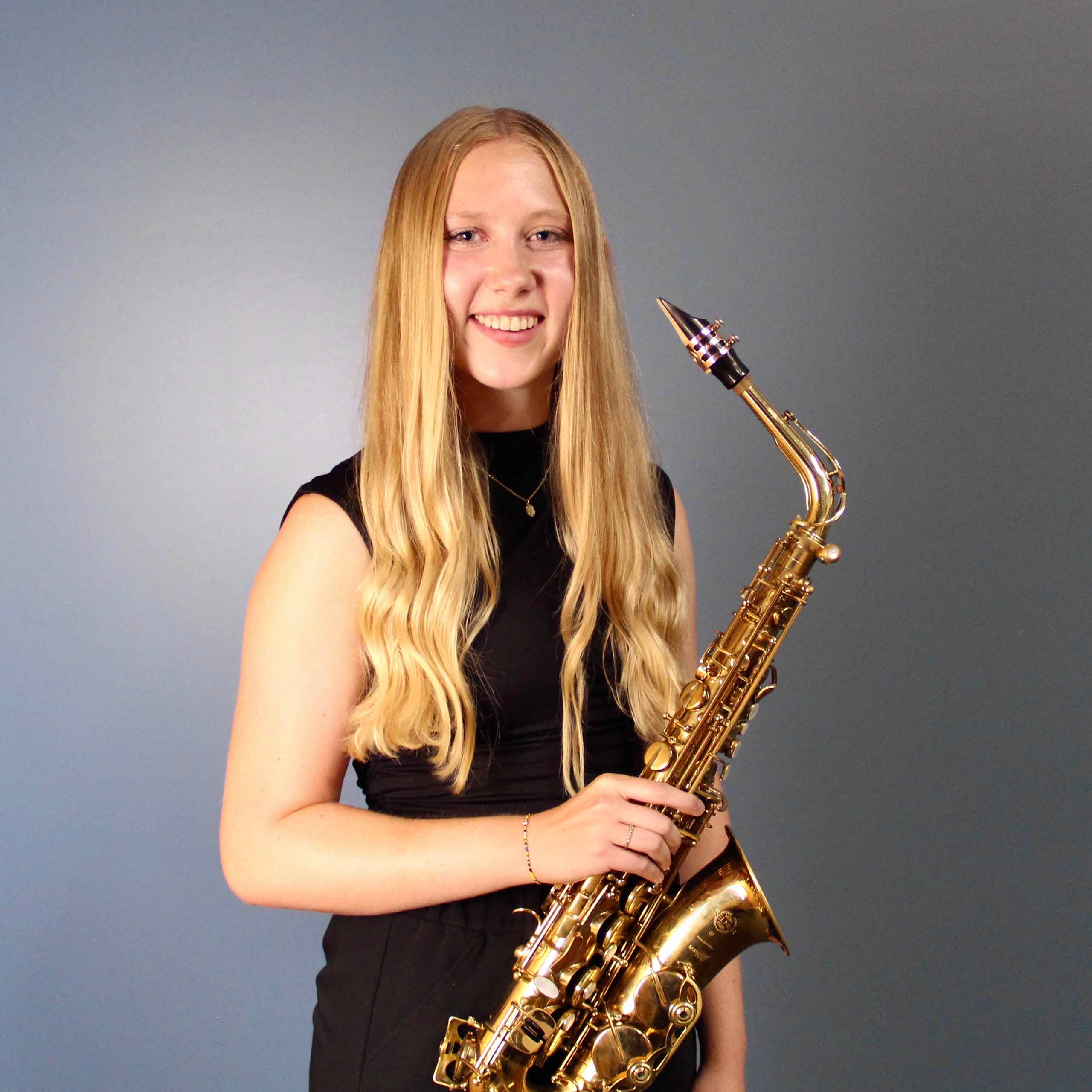 Standing studio portrait of Lauren Troutman holding saxophone.