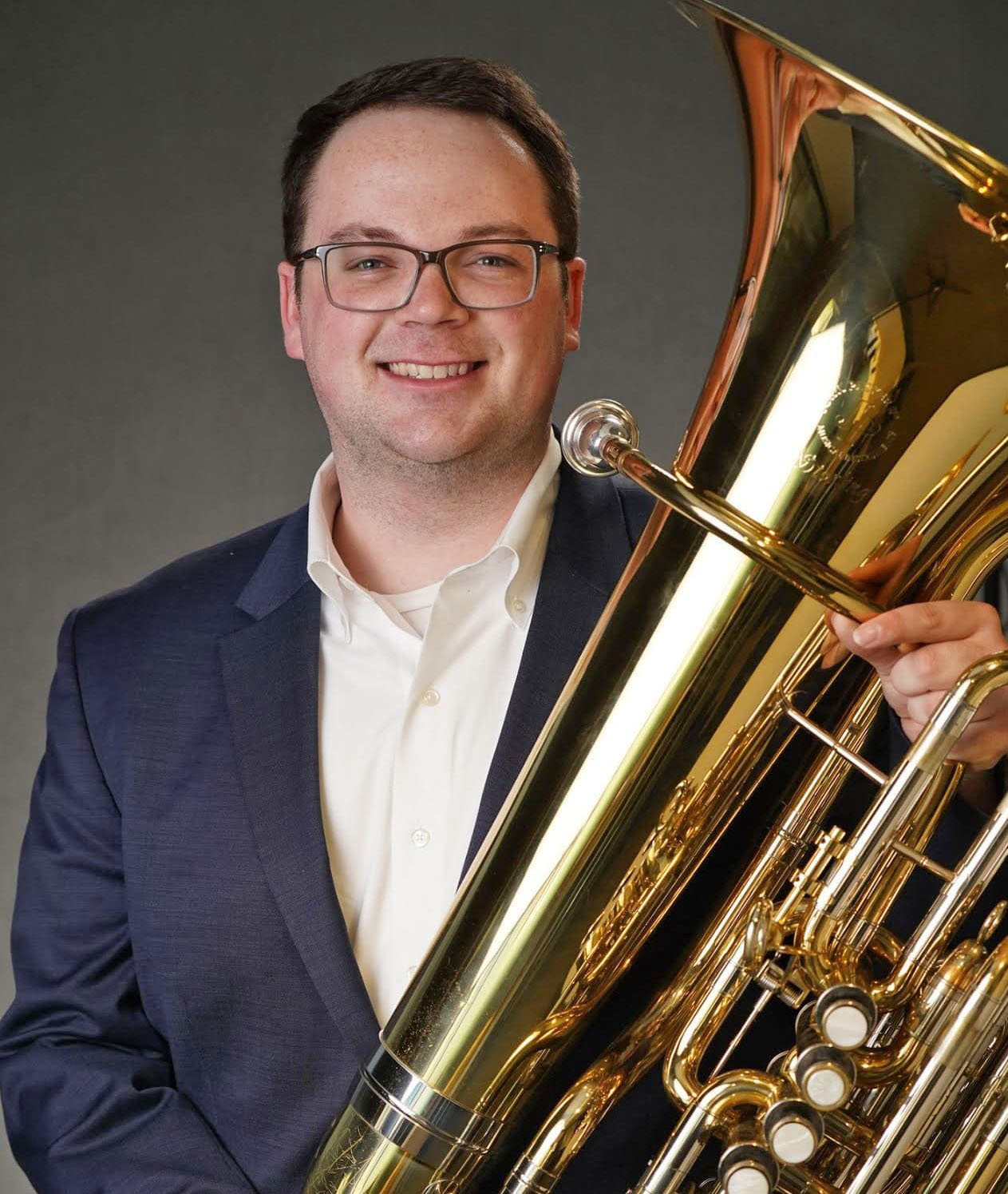 Studio portrait of Ryan Lofland holding his tuba.