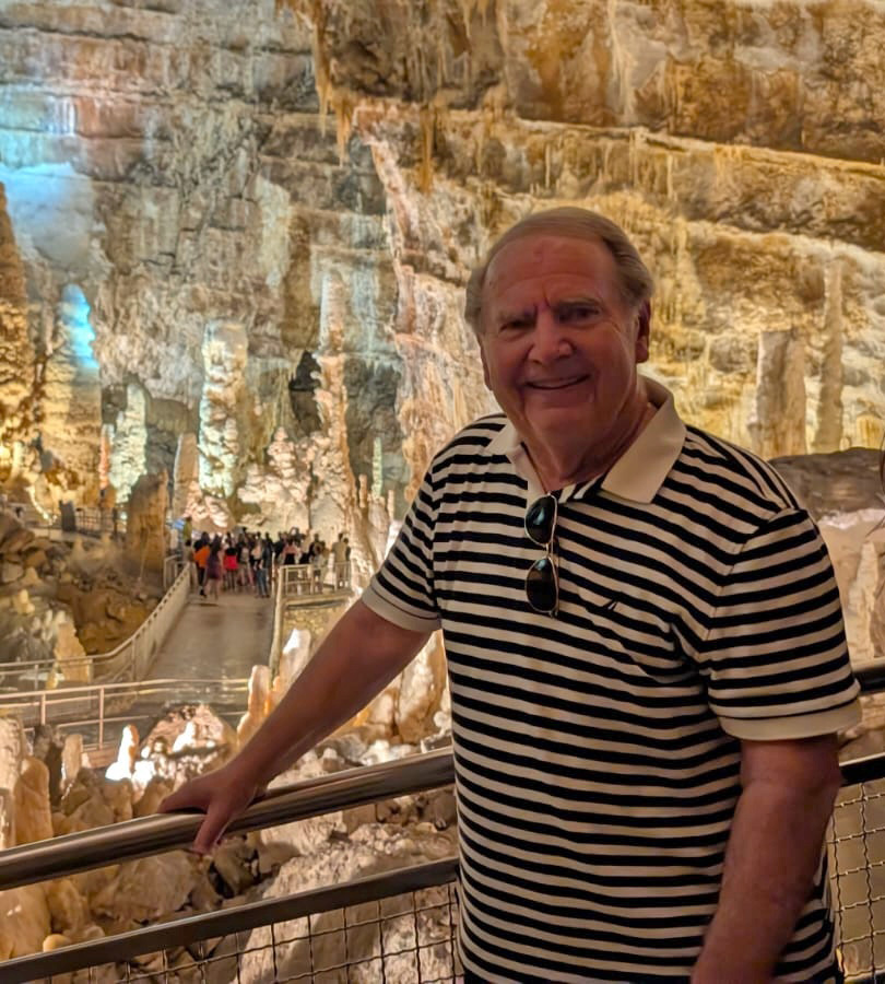 Brent Herhold poses standing on the balcony overlooking a huge cavern with walkways.