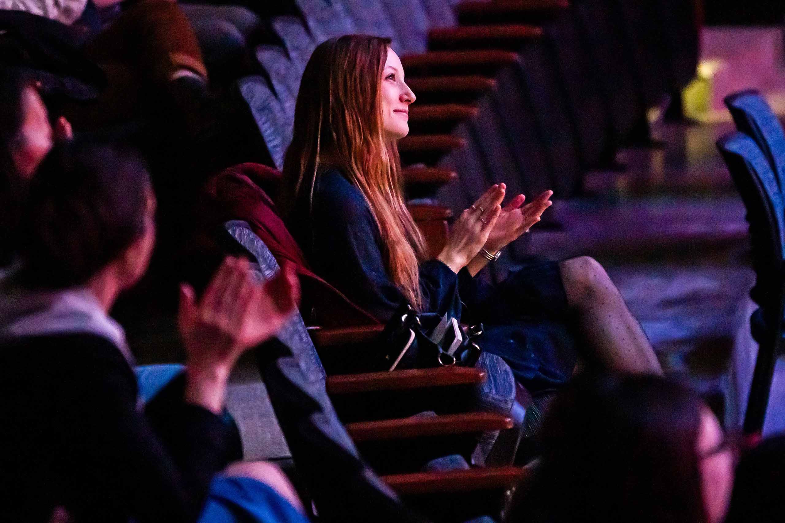 Gala Flagello Gala Flagello seated and clapping with other audience members during a performance.