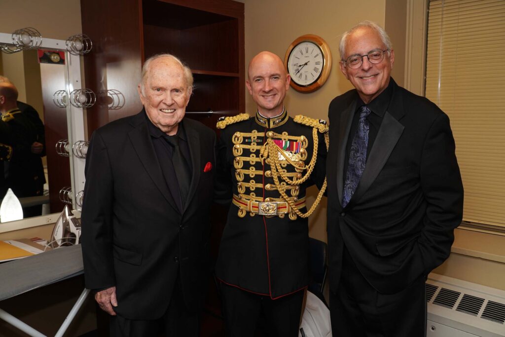 H. Robert Reynolds, Jason Fettig, and Michael Haithcock pose standing together and smiling backstage at Hill Auditorium.