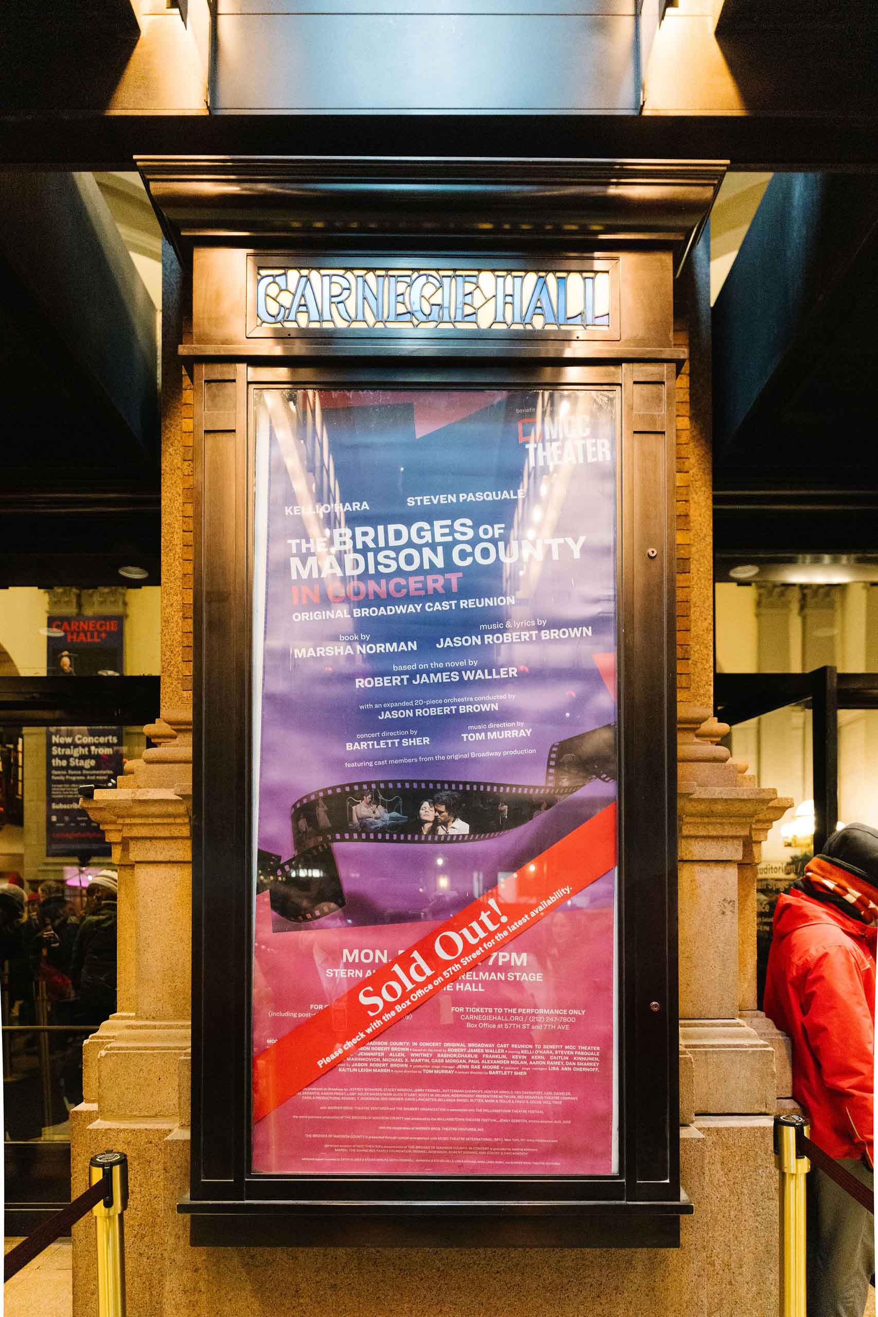 Inside a case with "Carngie Hall" in glass at the top, a poster for The Bridges of Madison County Concert is marked "Sold Out!"