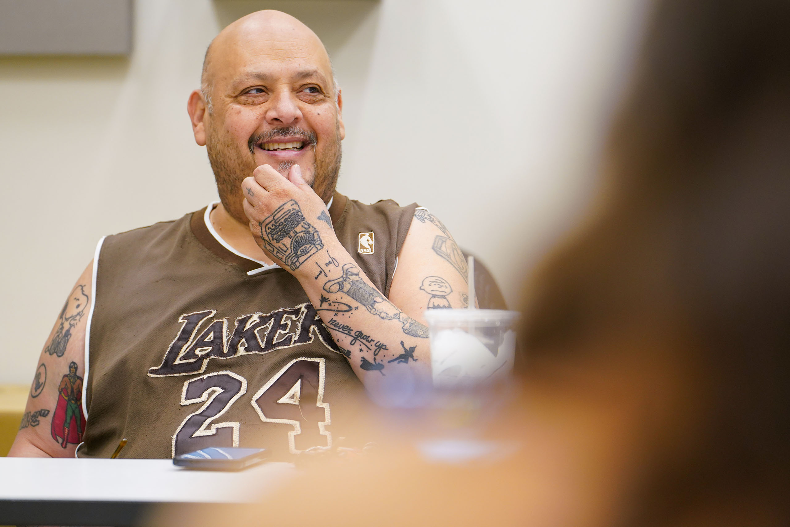Candid photo of José Casas seated at a table in conversation, with a blurry figure of someone facing him in the foreground.