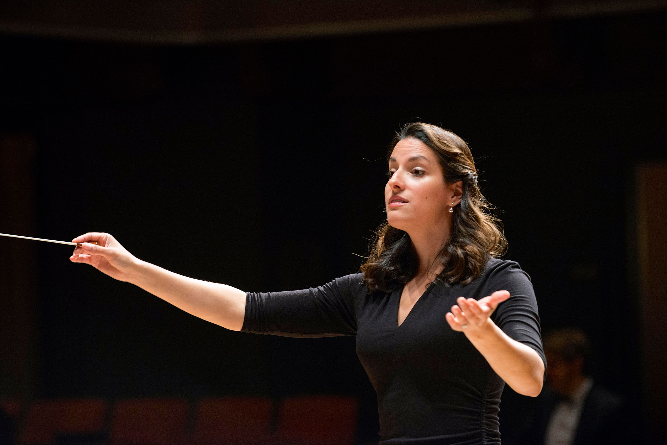 Levy highlight Patricia Cornett Photo Willa Rohrer Patricia Cornett holds a baton, conducting in a dark space.