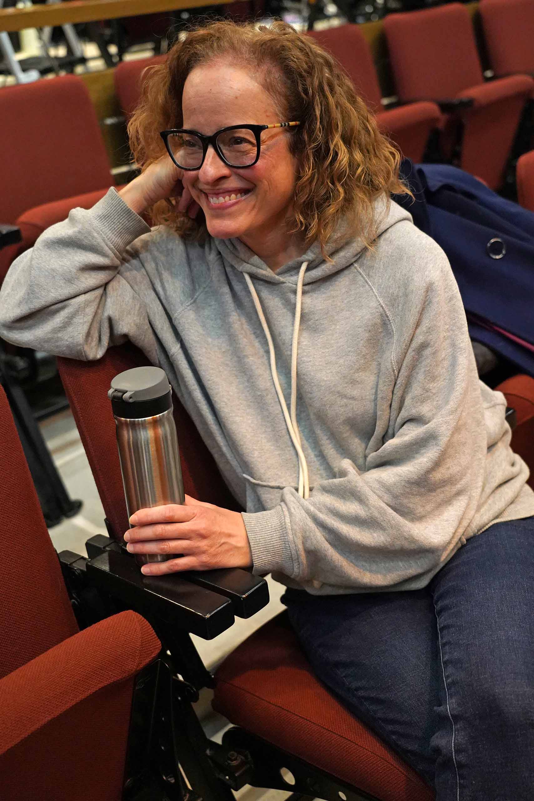 Candid photo of Lynne Shankel seated in a performance hall in casual attire.
