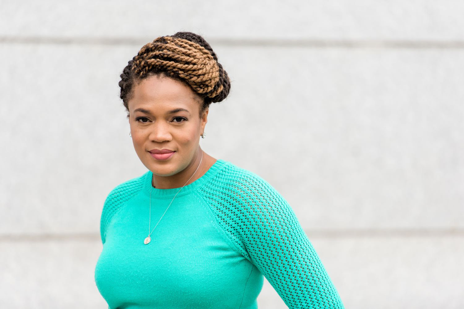 Portrait of Meredith Suttles standing next to a light concrete building.