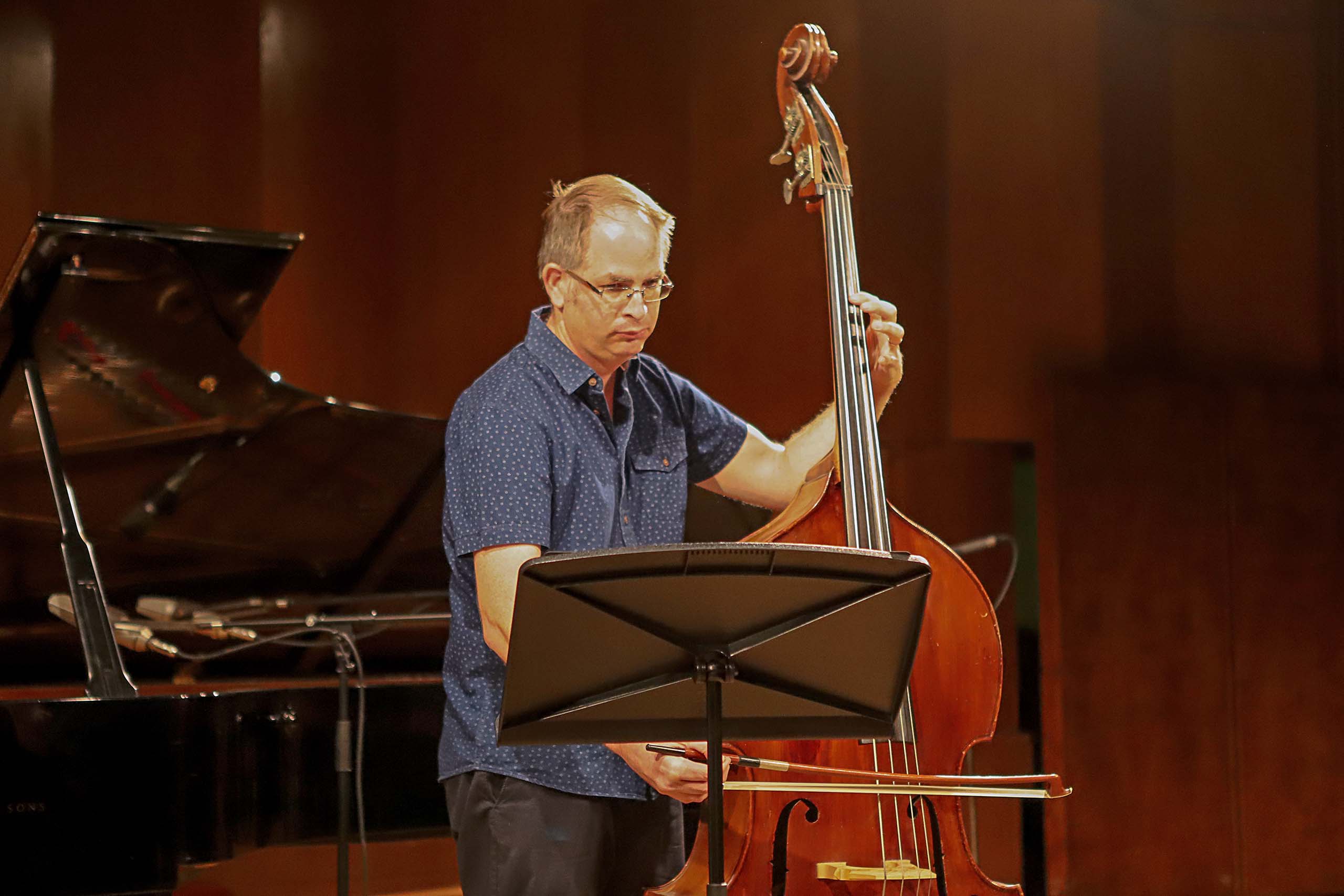 Ron Merhavi performs on double bass, with a grand piano visible in the background.