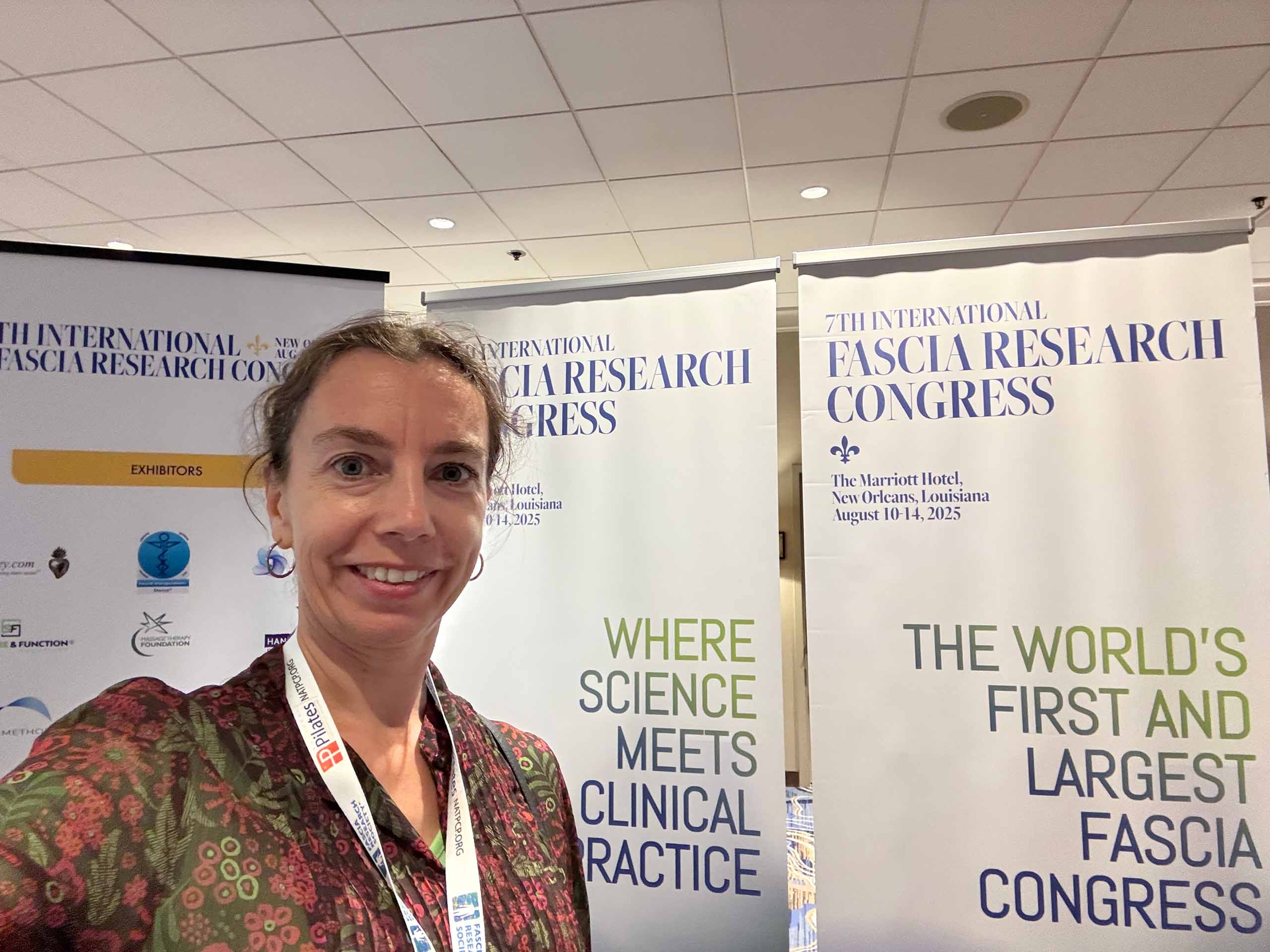 Selfie of Slávka Jelínková standing in front of tall conference banners, wearing a conference name tag.
