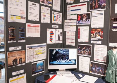 Justin Comini’s display featuring call sheets, a digital display, and production photos.