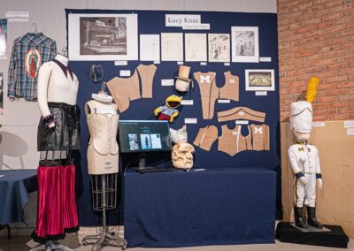 Lucy Knas’s display featuring costume sketches, models, and a digital display.