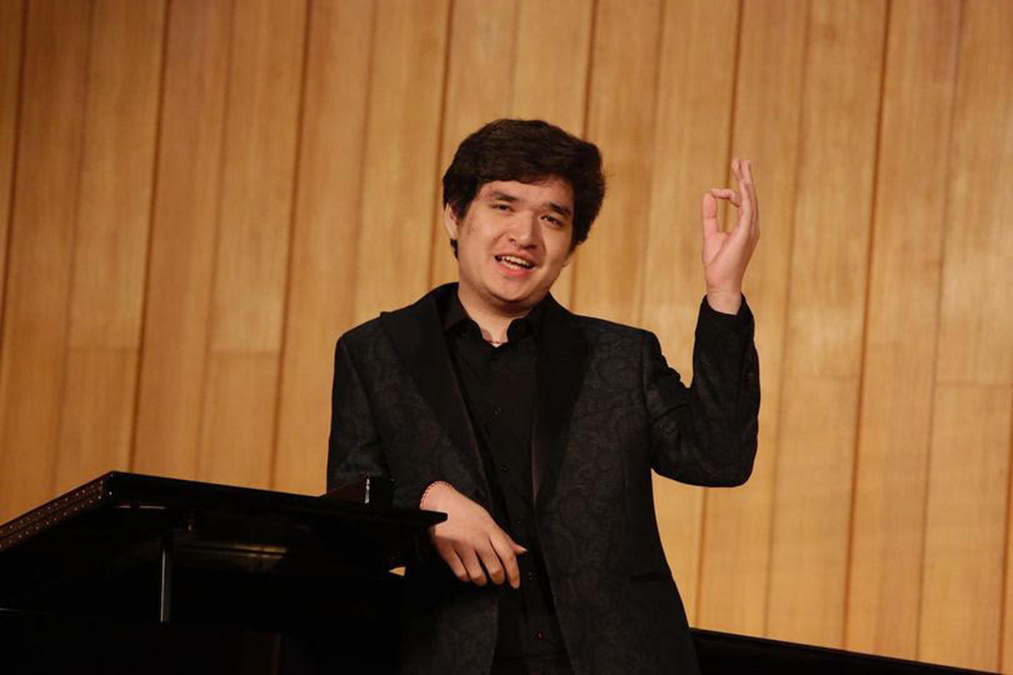 Plamen Fung speaks at a lectern with a hand raised in expression.