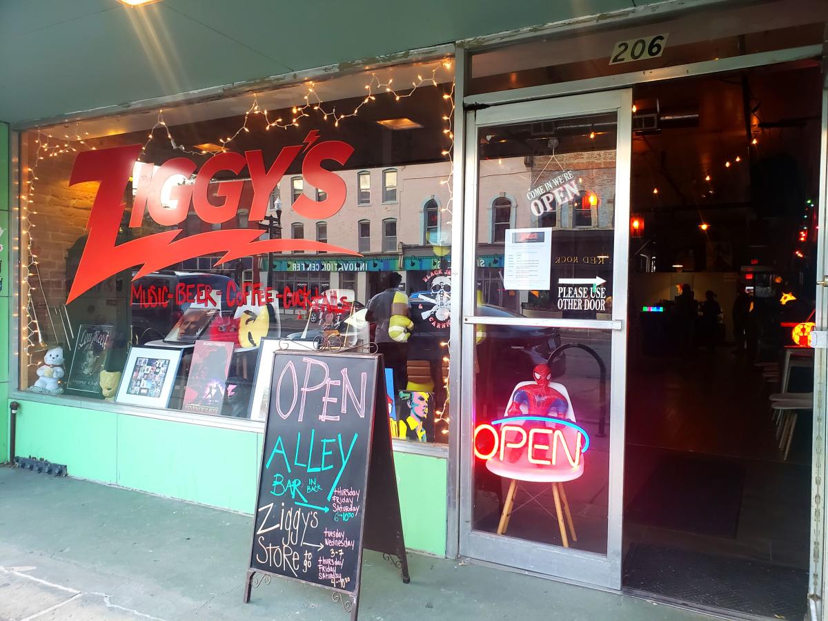 Ziggy's storefront and sidewalk with open door and open signs.