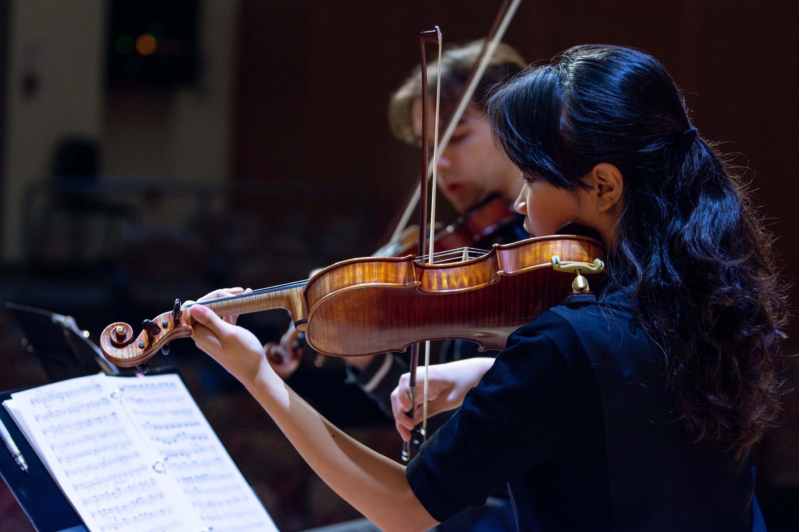 Two string players play music together.