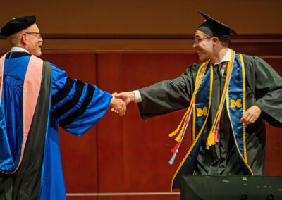 Dean David Gier shakes hands with a graduate on stage.