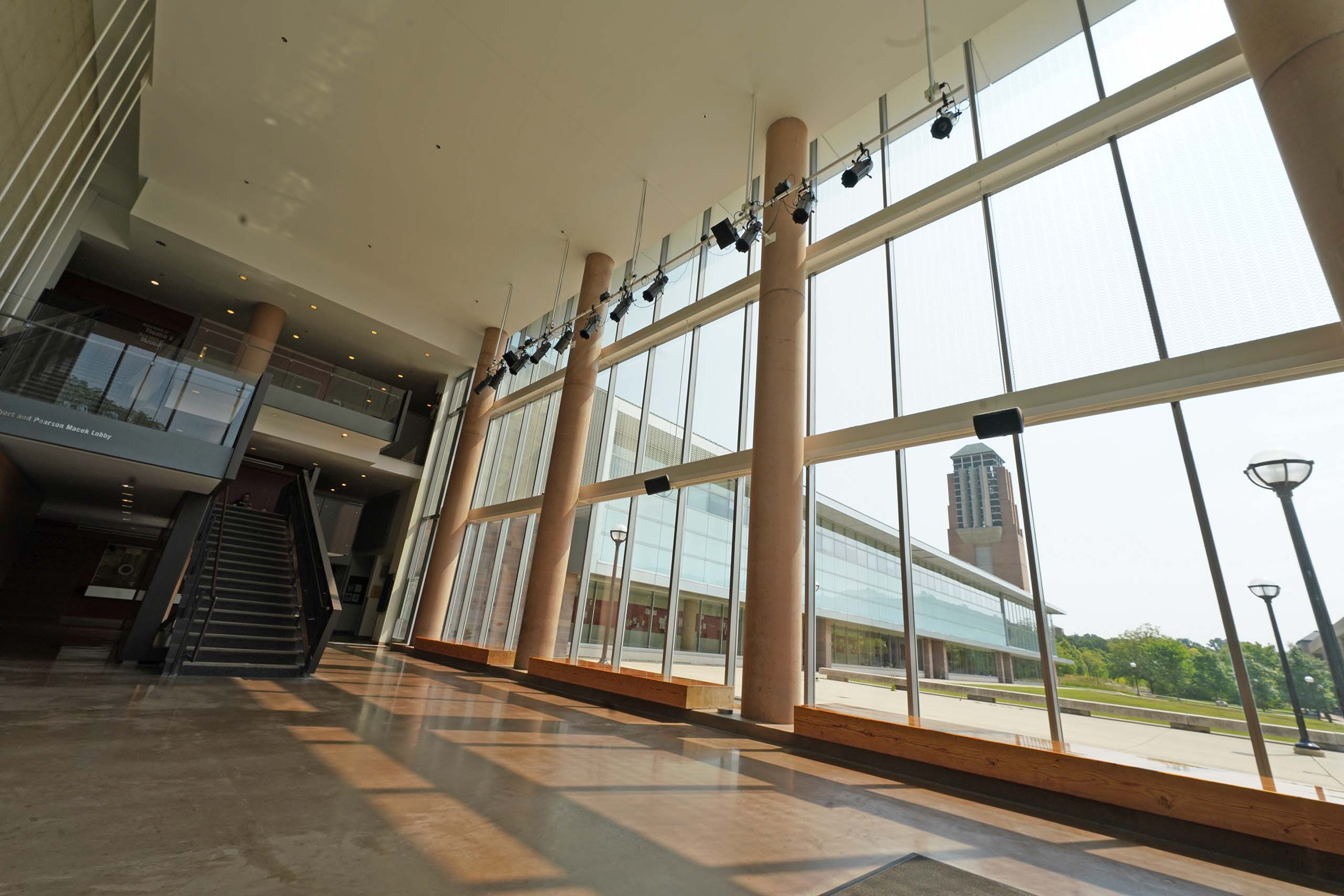 The interior of the two-story lobby at Walgreen Drama Center, with Lurie Tower visible outside through the lobby's glass wall.