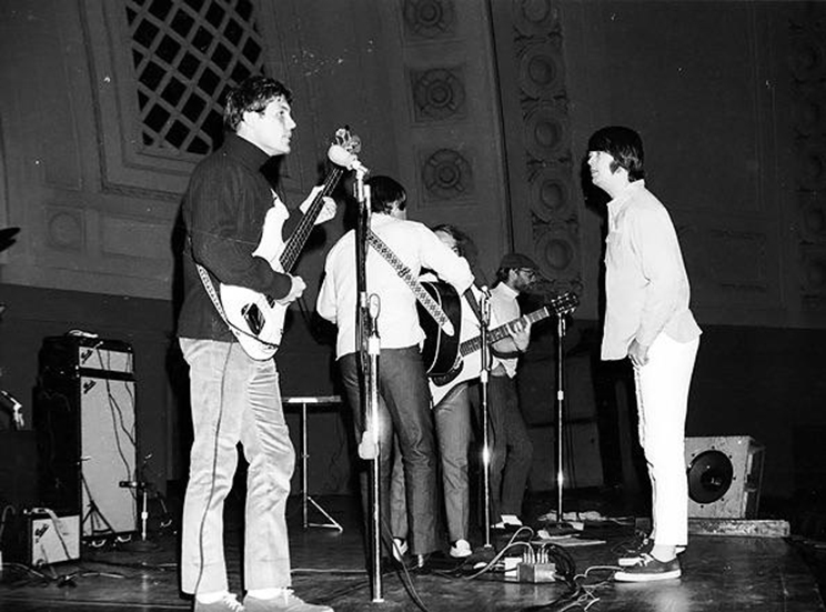 Greyscale historic photo of the Beach Boys playing on the stage of Hill Auditorium - apparently during a rehearsal.