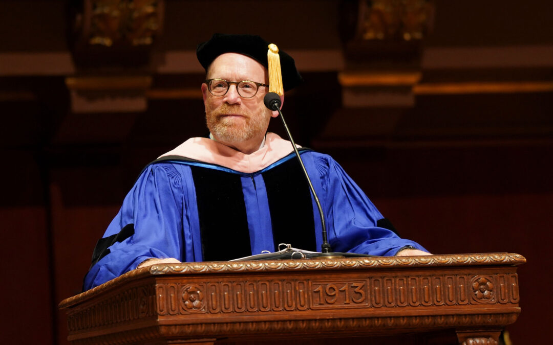 Dean Gier speaks at the historic podium in Hill Auditorium, attired in academic regalia for Commencement.