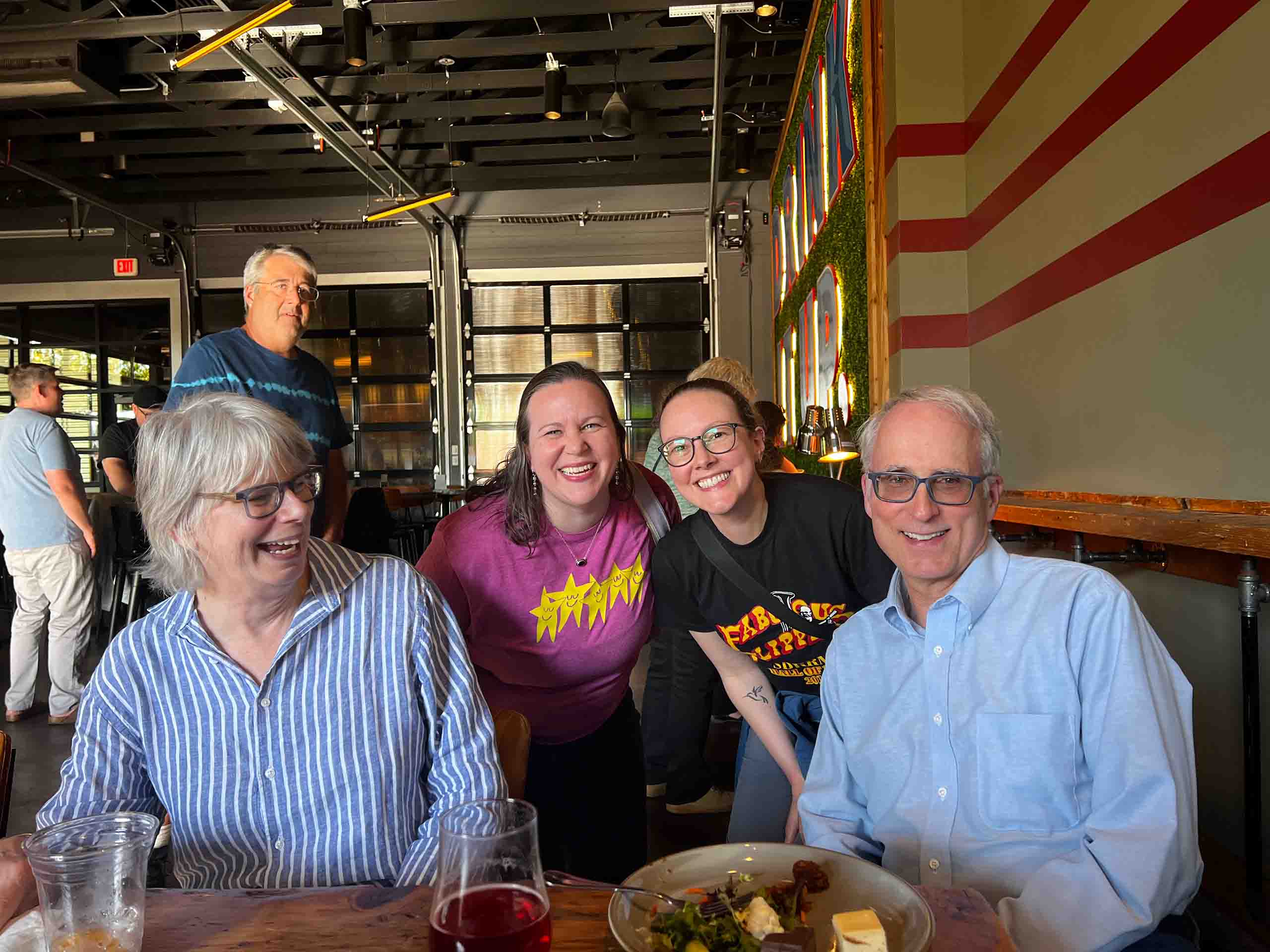 Casual photo of four people posing together at a restaurant table.