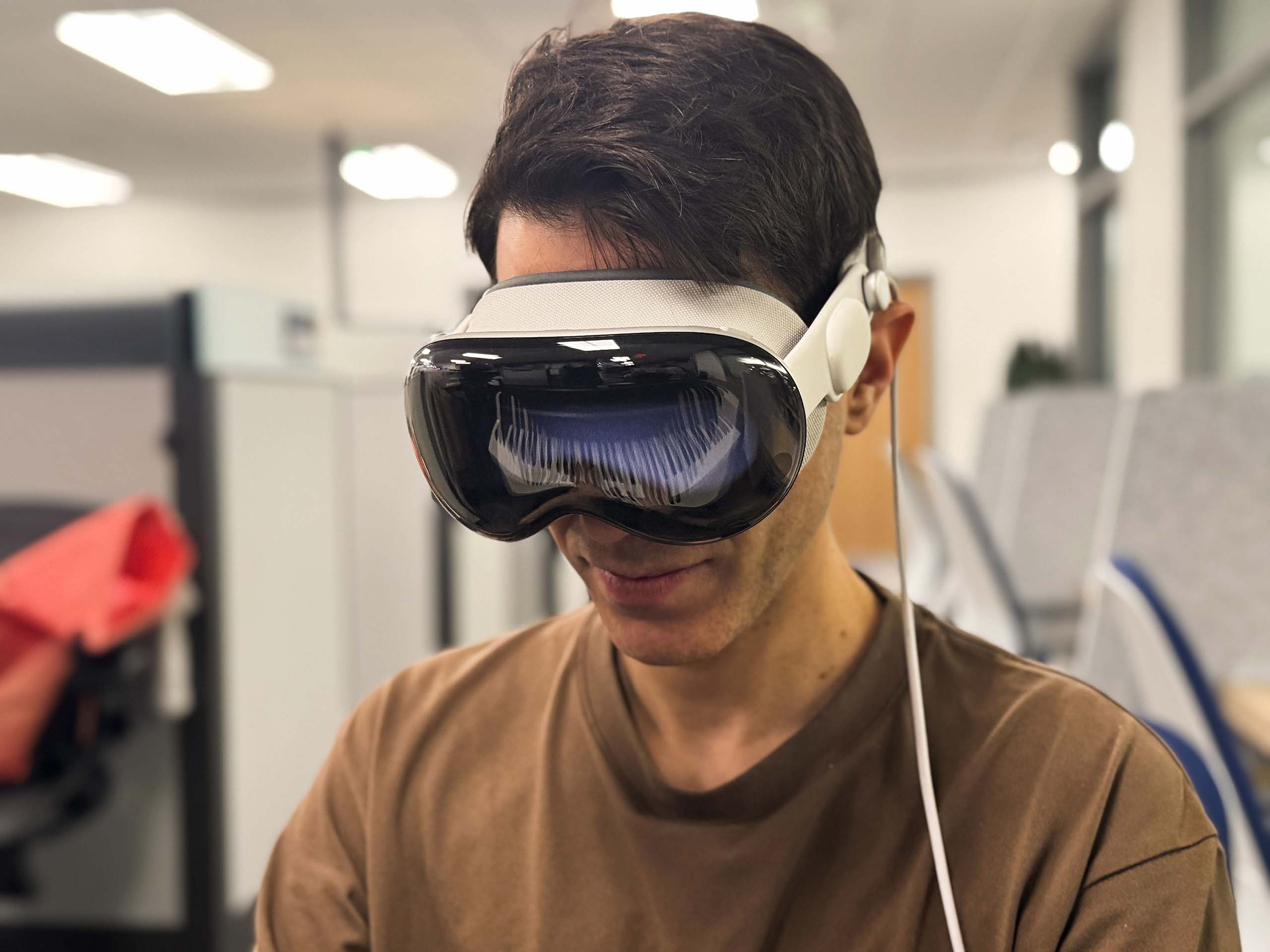 A person wears an extended reality headset, in which we see a reflection of piano keys in front of them.