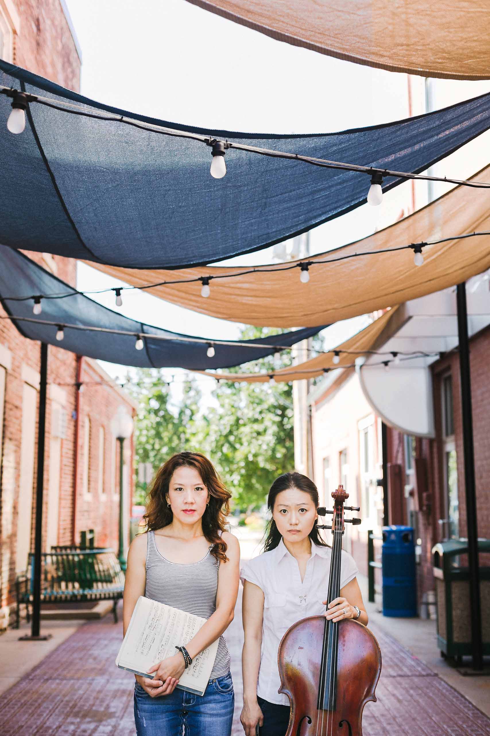 Standing casual outdoor portrait of Phoenix Park-Kim and Kristen Yeon-Ji Yun with cello.