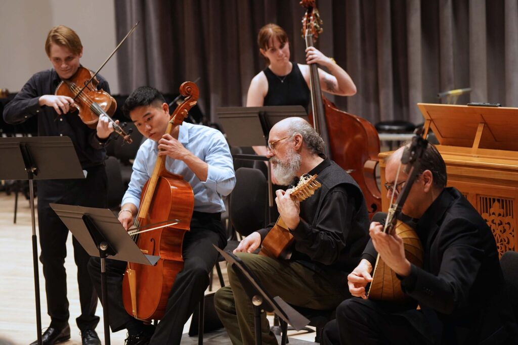 Five string players perform using music stands.