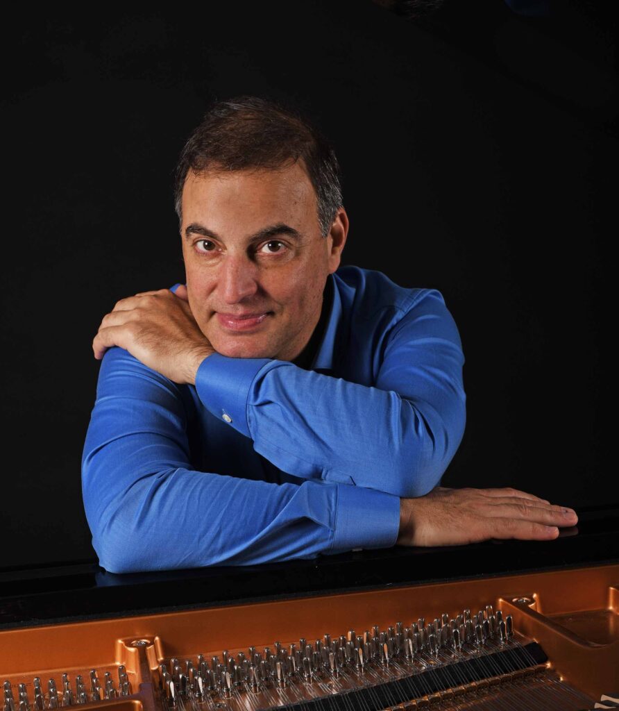 Studio portrait of Aviram Reichert with a piano.